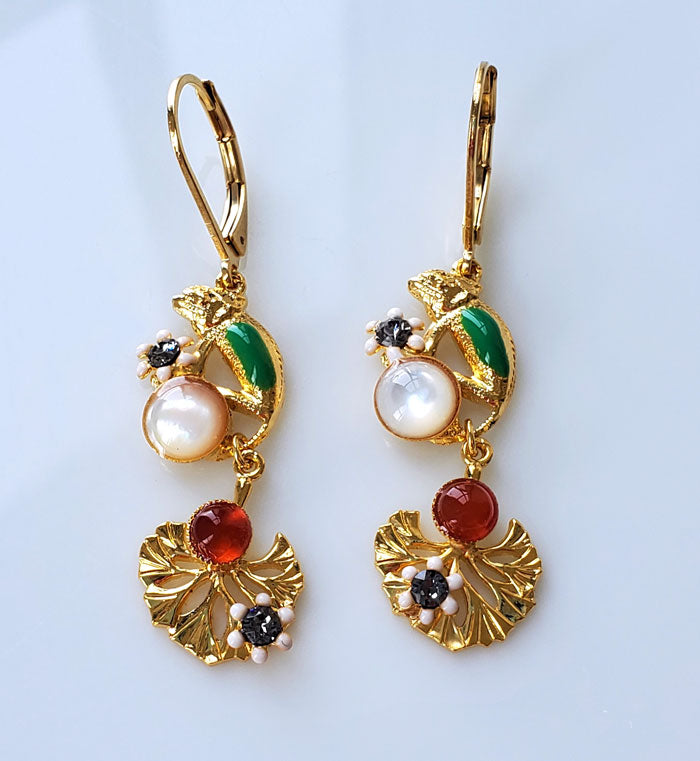 Boucles d'oreilles pendantes dorées à l'or fin 24 carats. motifs caméléon et fleur émaillées, cabochons en nacre et cornaline, strass Swarovski.