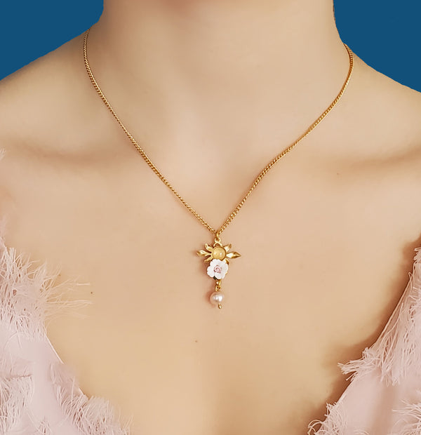 Collier fleur June doré à l'or fin. Cabochon en quartz rose sur feuillage doré, fleur blanche et perle d'eau douce rose.