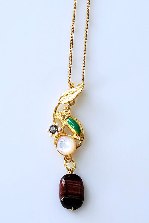 Tour de cou au motif caméléon. Doré à l'or fin, émail vert et blanc, cabochon en nacre, perle grain de café en agate, strass Swarovski.