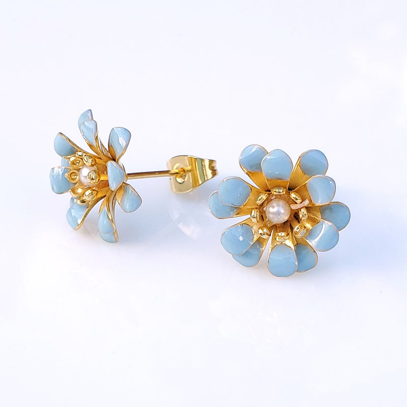 boucles d'oreilles percées, motif fleur pompon dorée à l'or fin 24 carats, petite fleur fantaisie au centre et pétales en relief émaillées coloris bleu ciel.  Modifier le texte alternatif