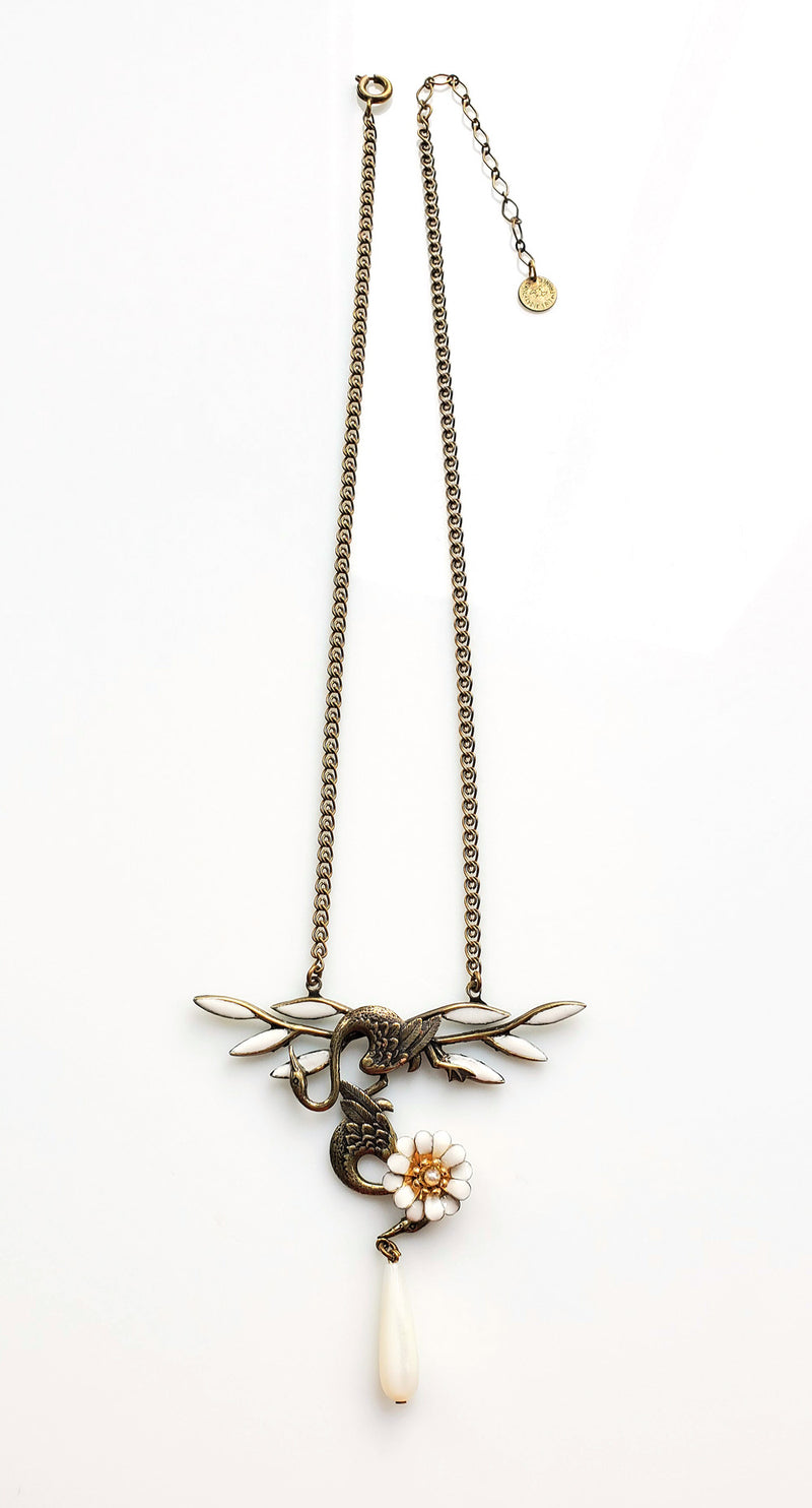 collier aux 2 cygnes enlacés, en métal plaqué bronze, émaillé blanc et goutte de nacre en pampille